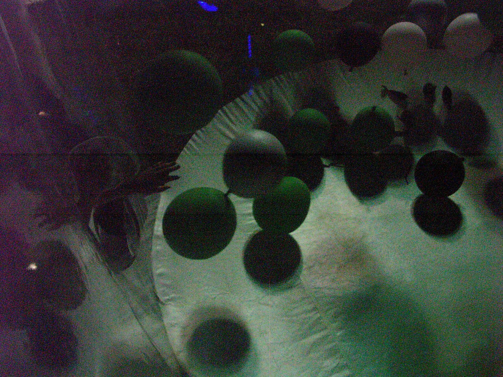 Green and dark orbs scattered across a pale dish, murky and abstract behind textured glass